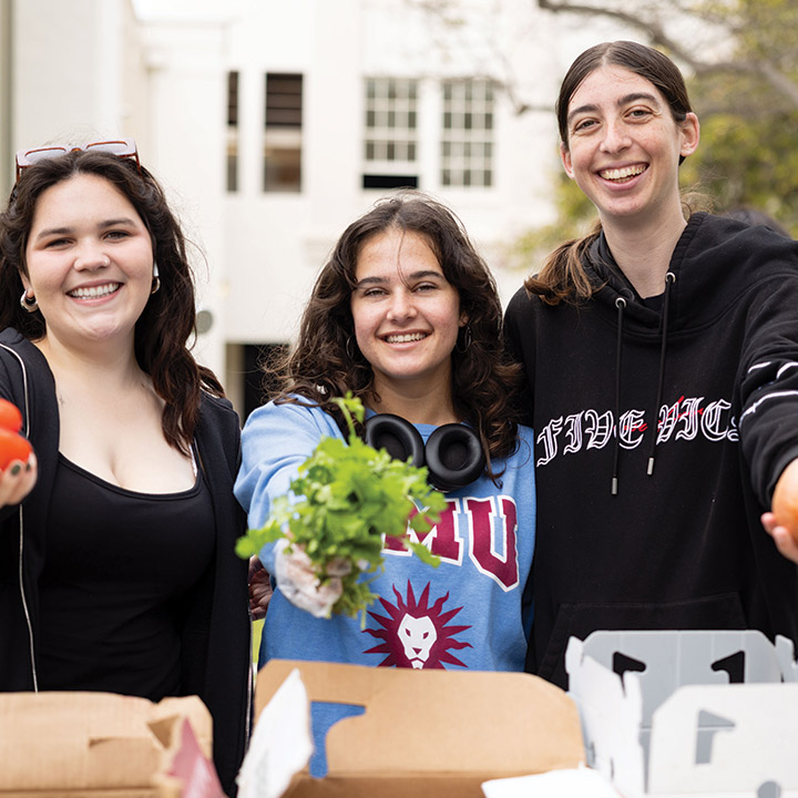 Three LMU students handing out produce