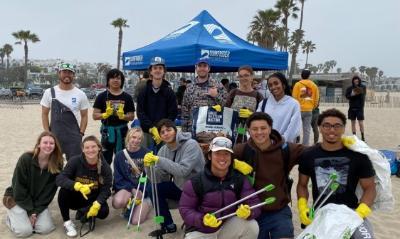 Students standing near a tent on the beach for a group photo