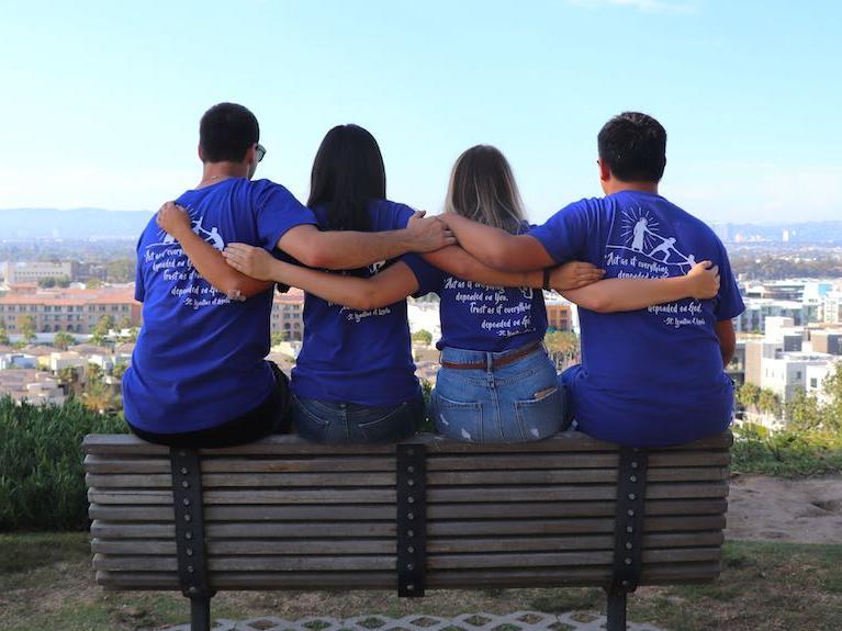 students on a bench overlooking the bluff with arms around each other