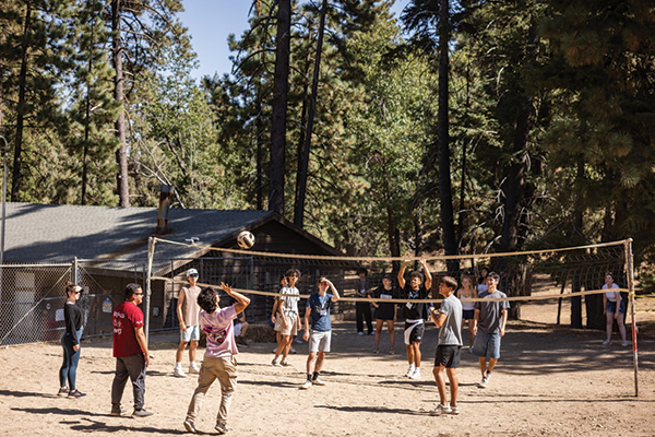 Volleyball Game outdoors with pine trees in the background