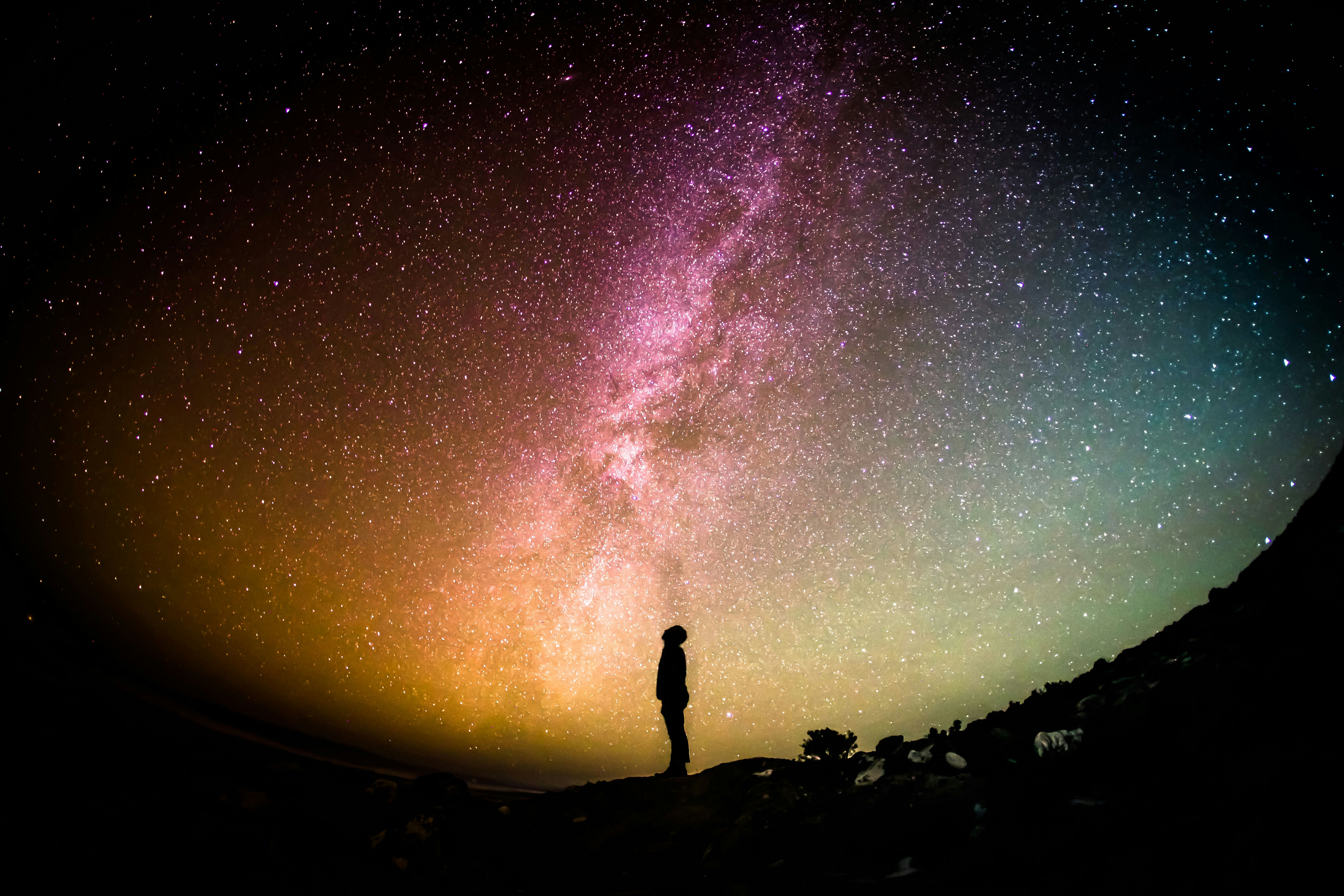 A male figure gazes up at the night sky with the Milky Way visible overhead