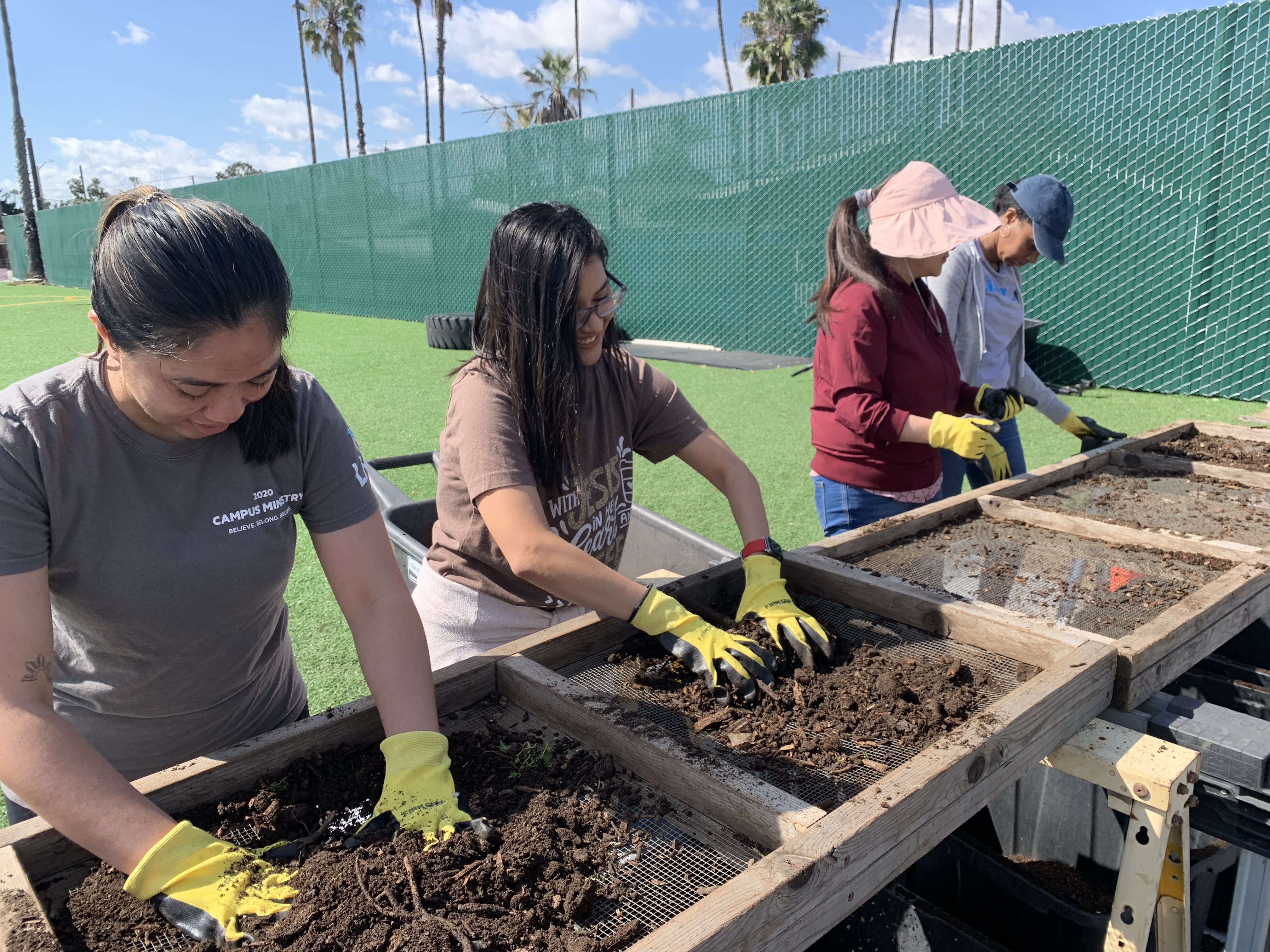 Three women sift compost at Alma Backyard Farms